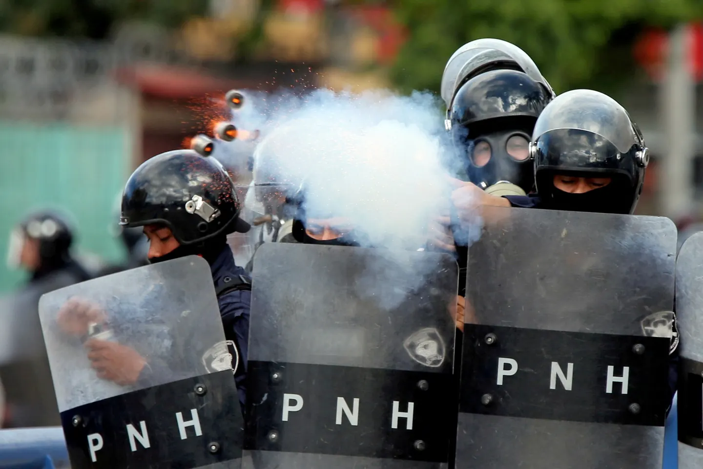 Foto de Edgard Garrido: policías antidisturbios con escudos PNH disparan gases lacrimógenos.
