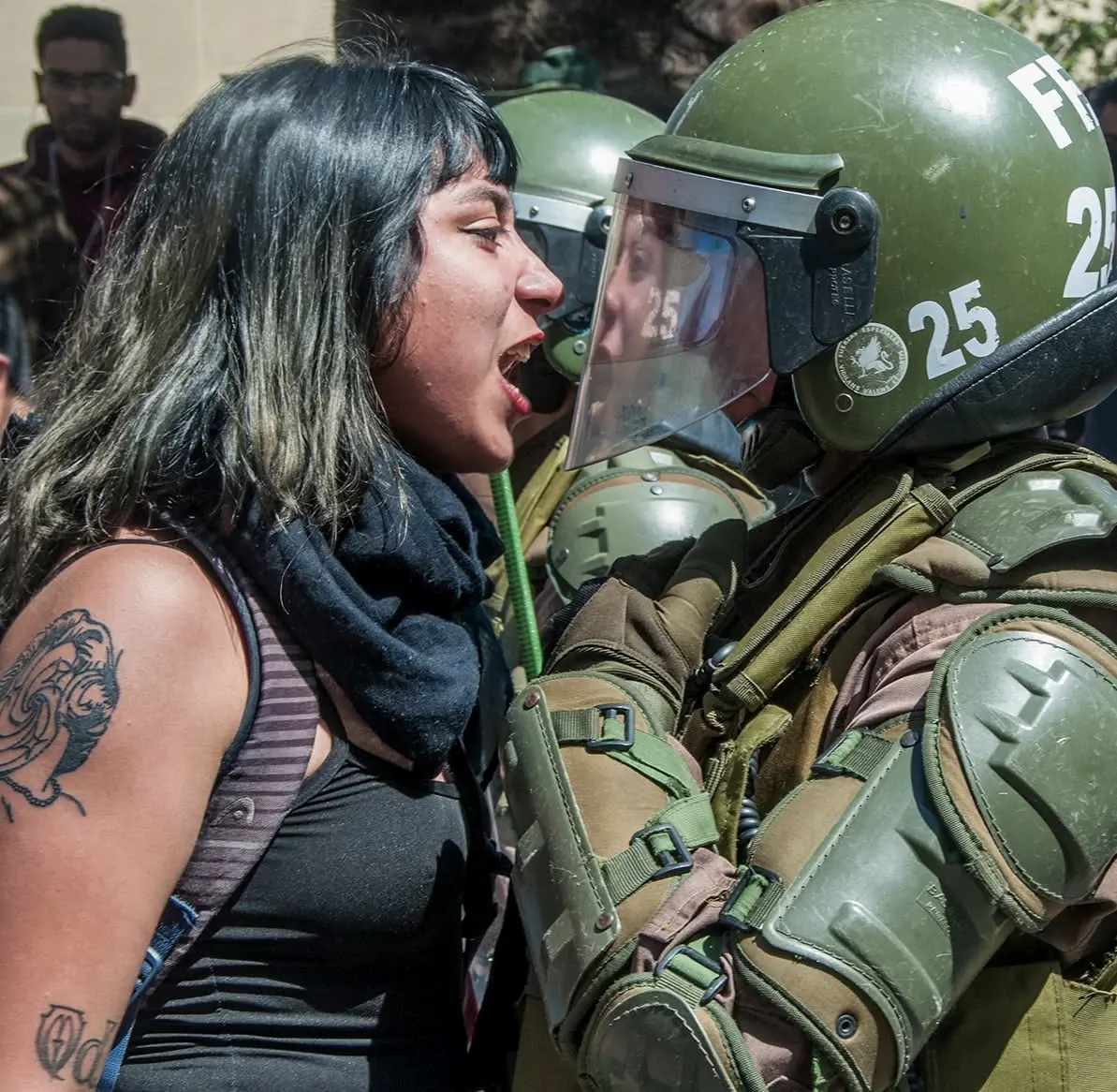 Foto de Héctor González de Cunco: una joven le grita de frente a un carabinero de fuerzas especiales con casco y visera.